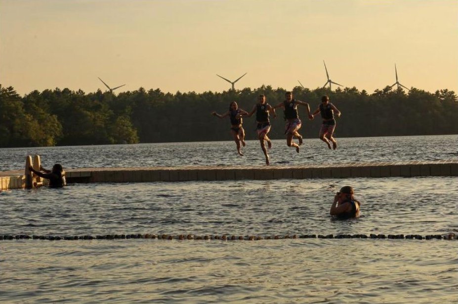 Campers jumping off a dock at golden hour at a YMCA of Pawtucket summer camp
